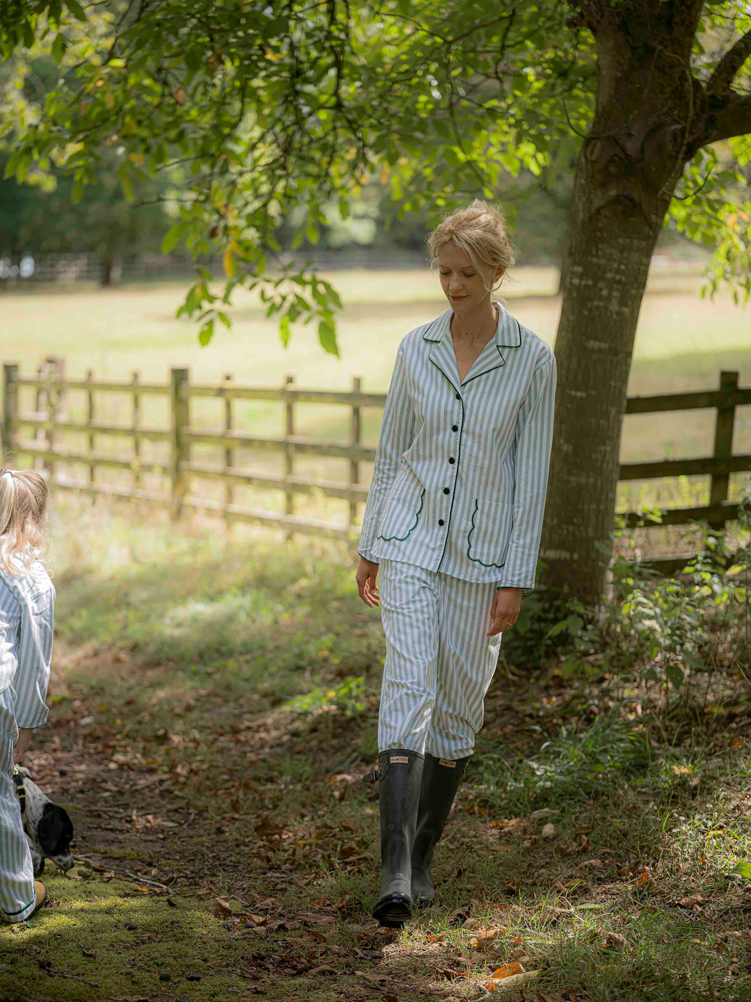 Woman wearing green striped brushed cotton pyjamas with scalloped pockets and hems from Siân Esther, made in Portugal using Better Cotton Initiative cotton, combining comfort and timeless elegance
