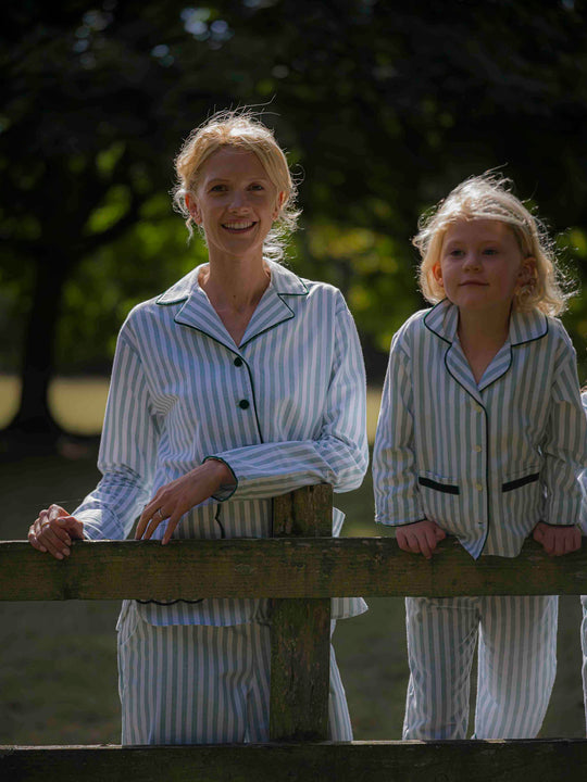 Woman and matching children's wearing green striped brushed cotton pyjamas with scalloped pockets and hems from Siân Esther, made in Portugal using Better Cotton Initiative cotton, combining comfort and timeless elegance