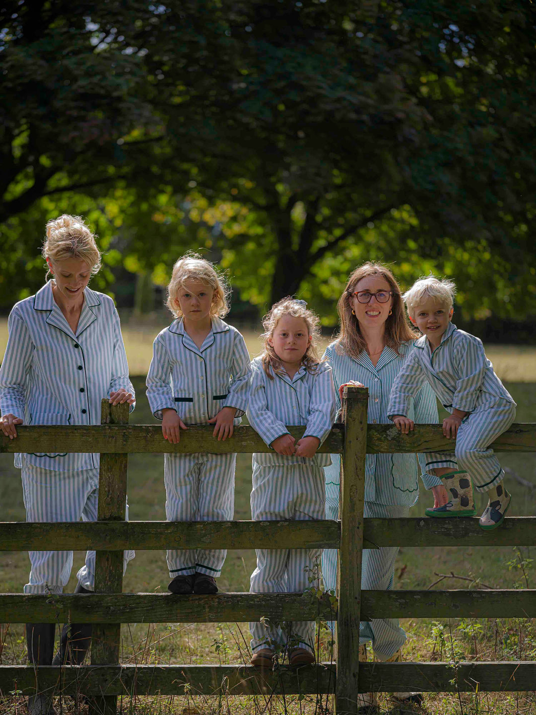 Woman and children wearing matching green striped brushed cotton pyjamas with scalloped pockets and hems from Siân Esther, made in Portugal using Better Cotton Initiative cotton, combining comfort and timeless elegance