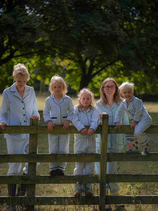 Woman and children wearing matching green striped brushed cotton pyjamas with scalloped pockets and hems from Siân Esther, made in Portugal using Better Cotton Initiative cotton, combining comfort and timeless elegance