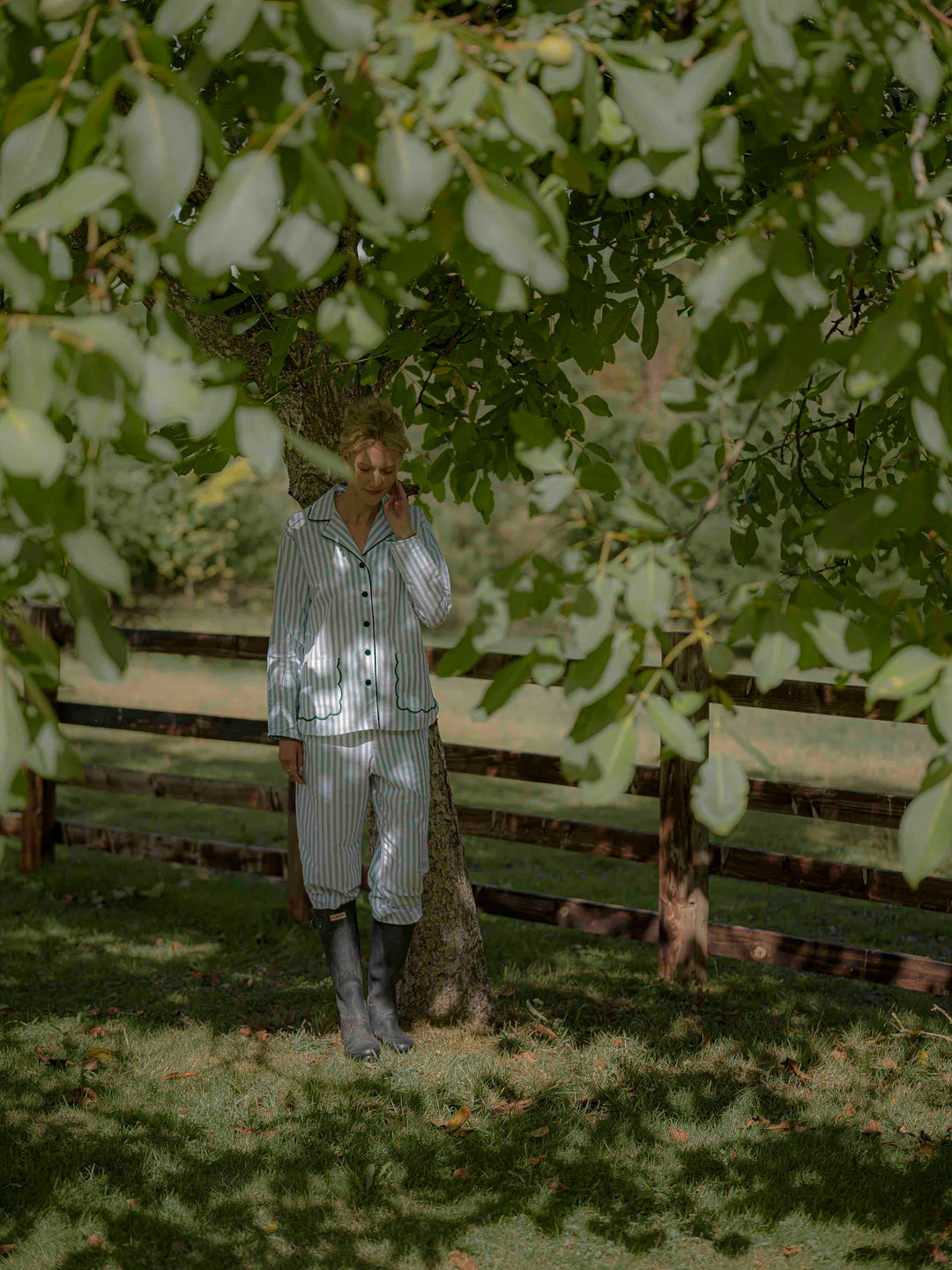 Woman wearing green striped brushed cotton pyjamas with scalloped pockets and hems from Siân Esther, made in Portugal using Better Cotton Initiative cotton, combining comfort and timeless elegance